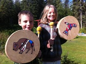 A boy and girl play with their homemade drums